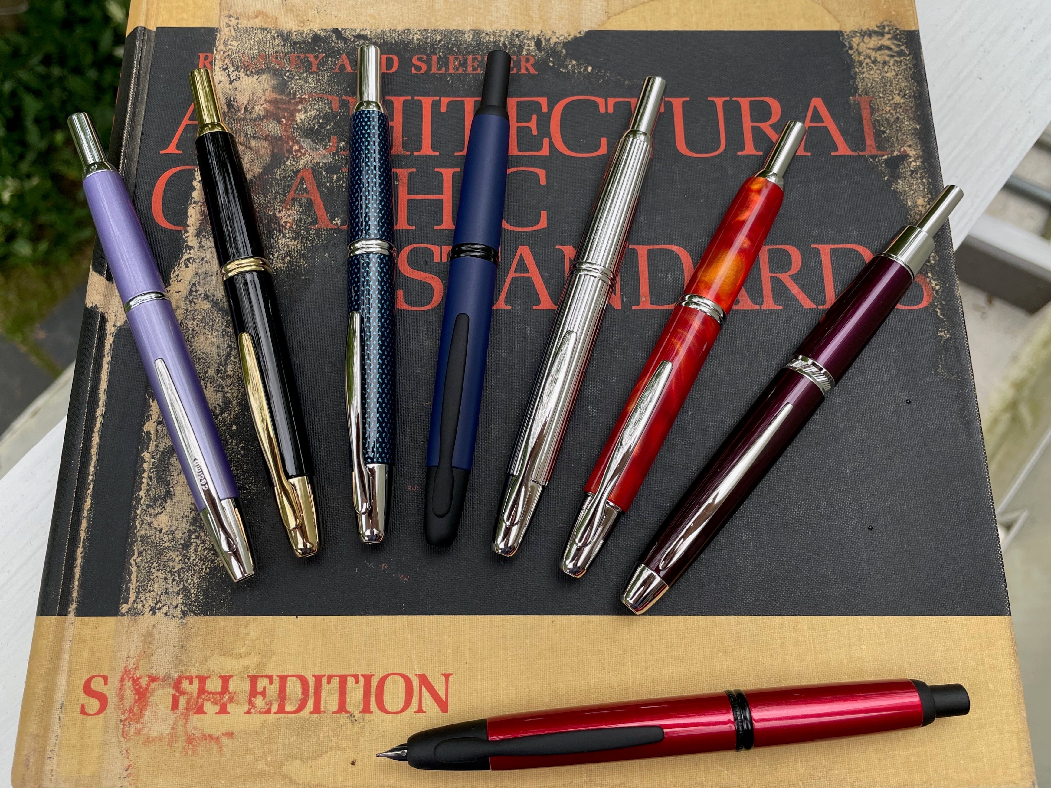 Eight Pilot Vanishing Point pens lying on an architectural book